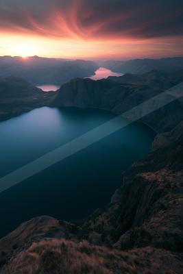 A moody landscape of mountains, lake, valley.