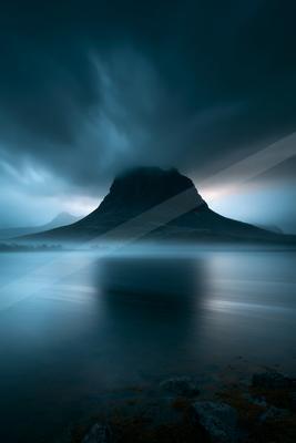 A blue hour long exposure landscape of mountains, ocean, lake.