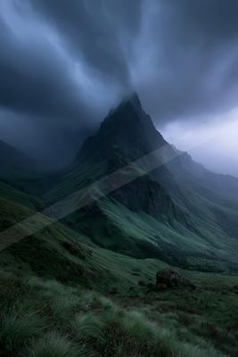 A sharp rocky mountain peak rises through thick, dark storm clouds above rolling green hills and grassy foreground.