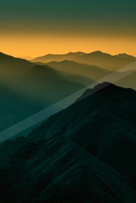 Silhouetted mountain ranges under a gradient sky transitioning from dark blue to warm orange hues.