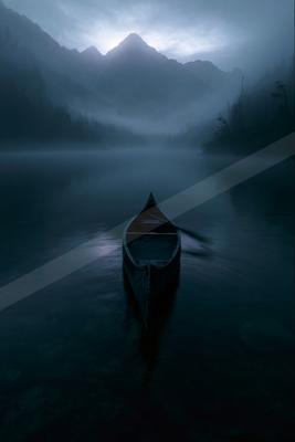 A wooden canoe floats on a calm, misty lake with forested mountains rising in the foggy background under a dramatic overcast sky.