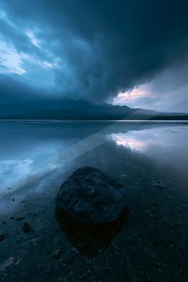 A blue hour long exposure water scene of lake, storm, clouds.