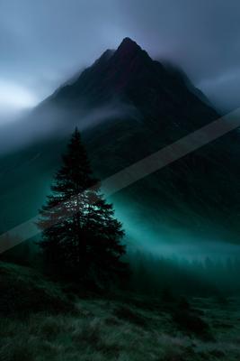A dramatic mountain peak shrouded in mist, illuminated by a mysterious green glow, with a prominent pine tree silhouetted in the foreground.
