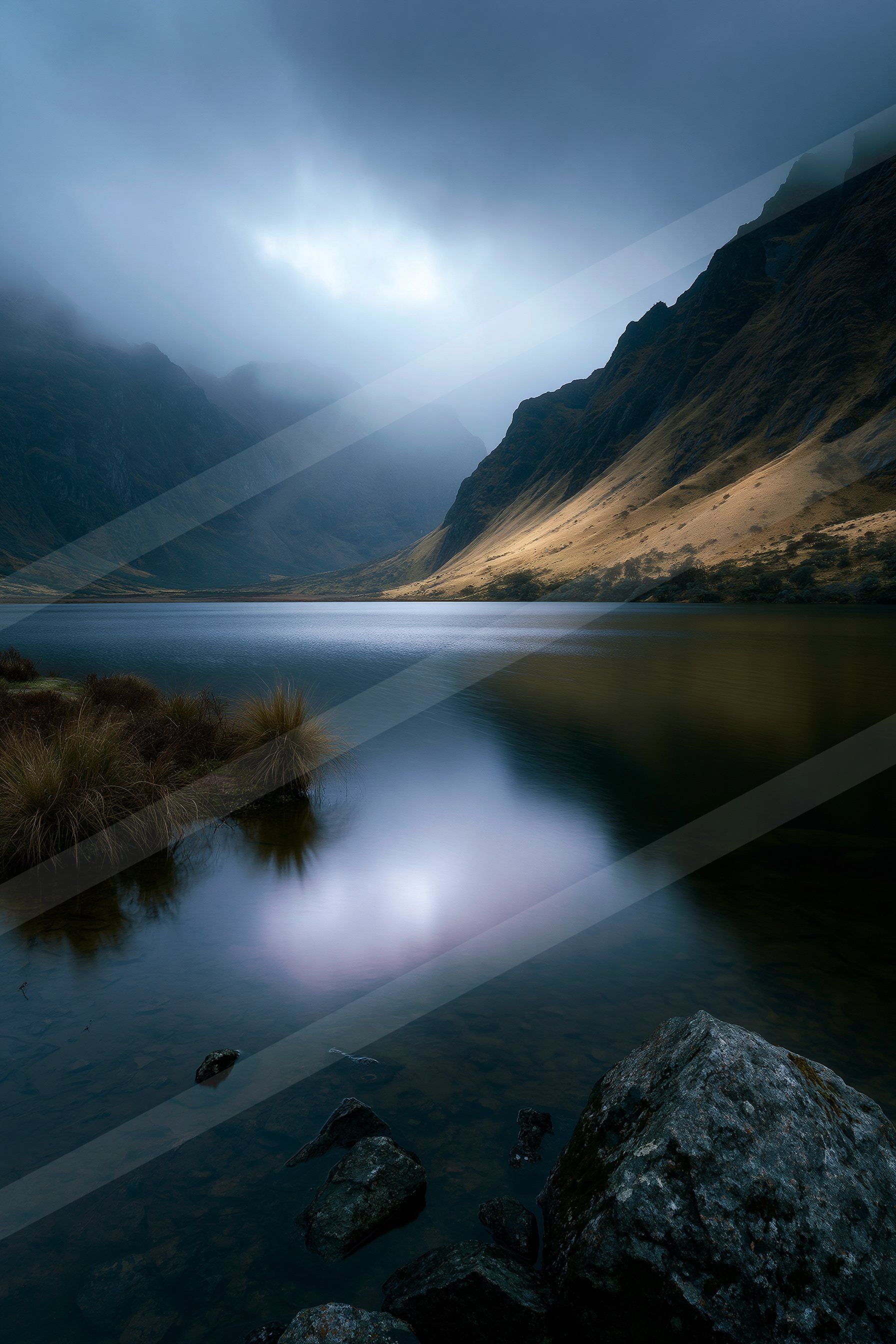 A serene lake surrounded by rugged mountains under a foggy sky, reflecting the ethereal light above.