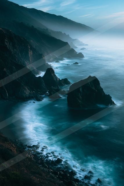 A blue hour long exposure water scene of a coastline, fog.