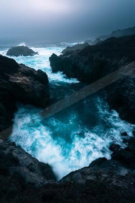 A blue hour long exposure water scene of ocean, rocks.