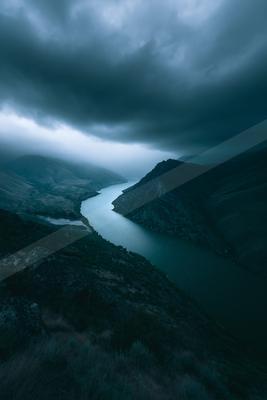 A black-toned moody photograph of valley, dam, lakeside.