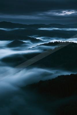 A blue hour long exposure landscape of mountains, valley, clouds.