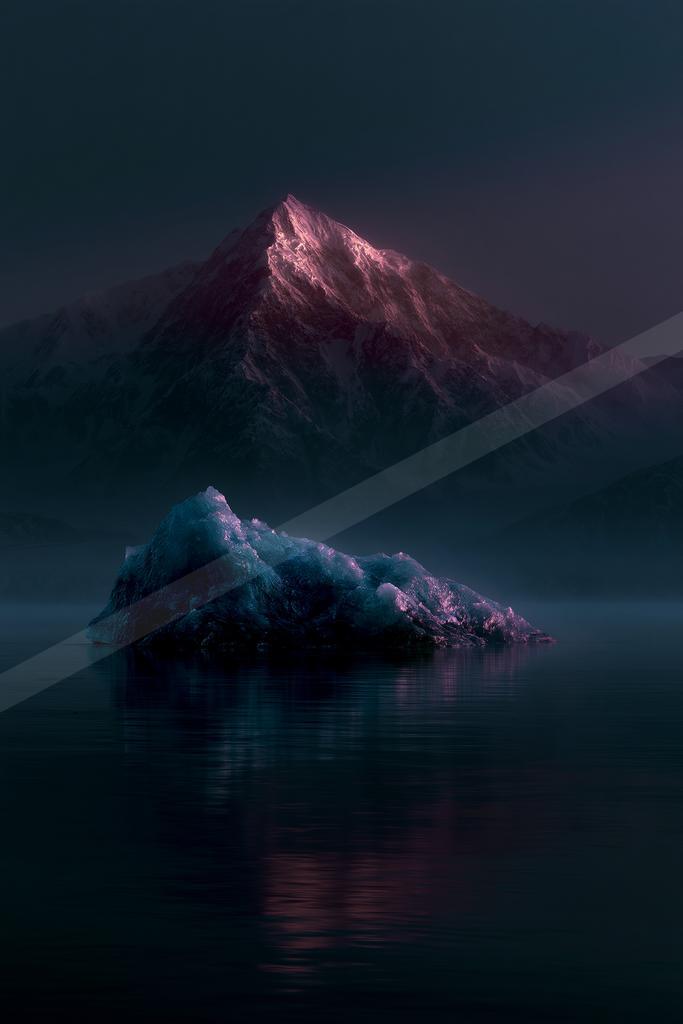 A large blue iceberg floats in calm dark water, reflecting pink and purple light, with a massive snow-covered mountain peak glowing in the background under a da