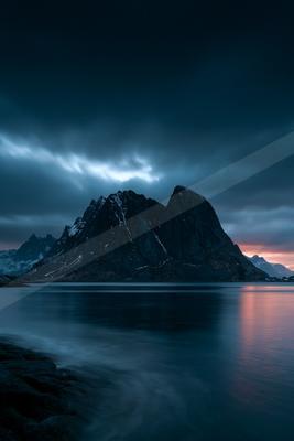 A blue hour long exposure landscape of mountains, storm, ocean.