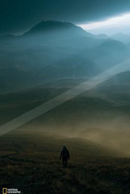 A dramatic landscape of mountains, field, valley.