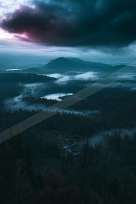 A blue hour landscape of mountains, valley, clouds.