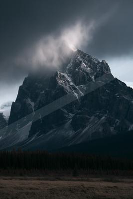 A dramatic landscape of mountains, fog.