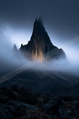 A dramatic landscape of mountains, fog.