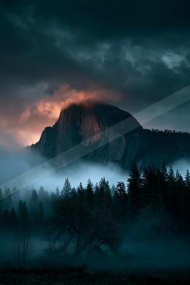 A dramatic landscape of mountains, storm, sunrise.