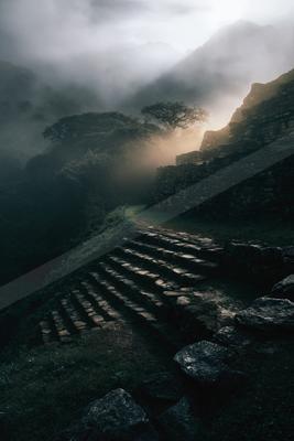 A black-and-white dramatic landscape of mountains, valley, fog.