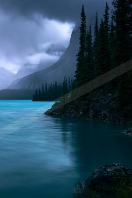 A blue hour water scene of lake, mountains, valley.