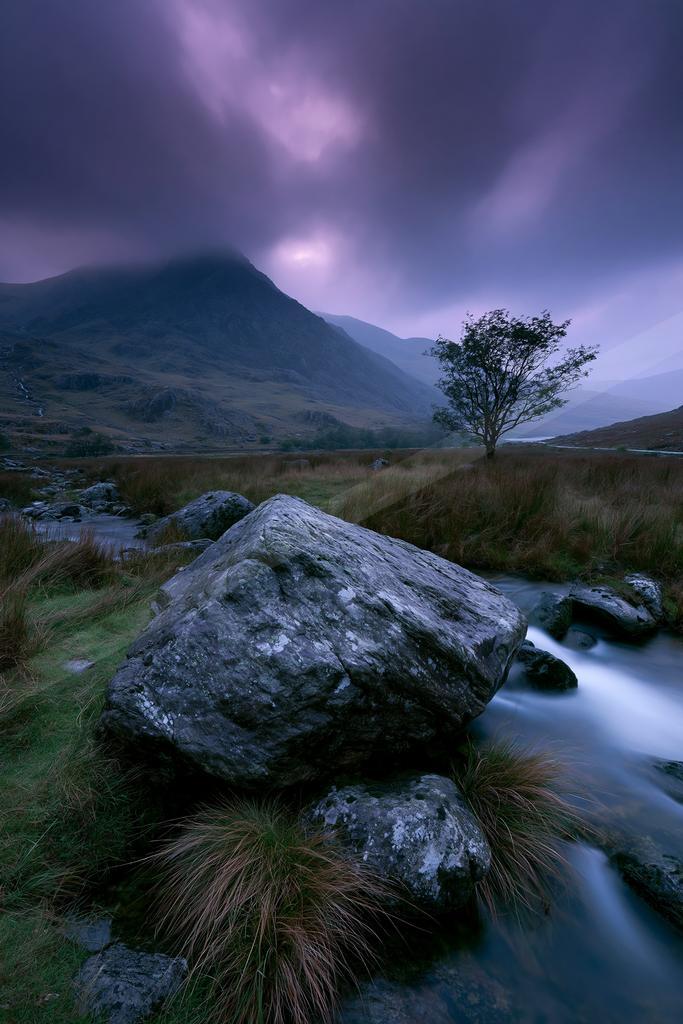 A serene long exposure water scene of river, valley, mountains.