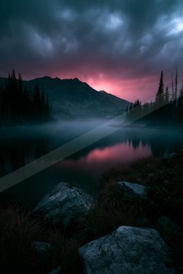A blue hour water scene of lake, mountains, sunset.