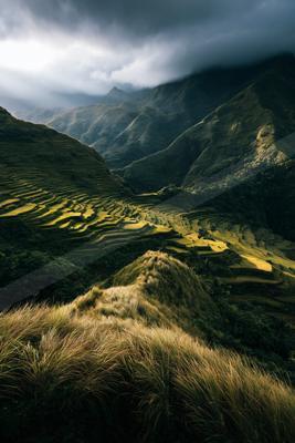 A moody landscape of valley, mountains, field.