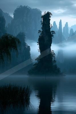 A serene water scene of lake, mountains, trees.
