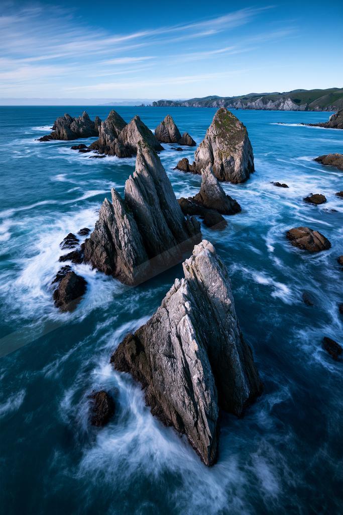 A blue hour long exposure water scene of ocean, beach, rocks.