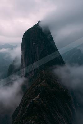 A moody landscape of mountains, fog.