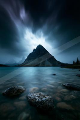A blue hour landscape of mountains, lake, storm.