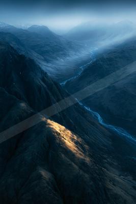 A blue hour landscape of valley, mountains, river.