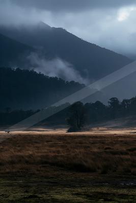 A brown-toned moody photograph of valley, alp, volcano.