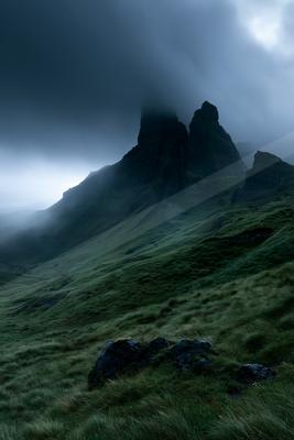 A black-toned moody photograph of volcano, mountain tent, cliff.