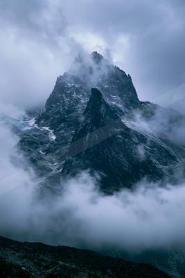A dramatic landscape of mountains, fog.