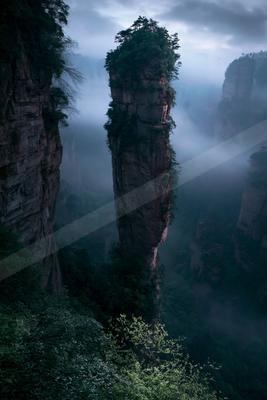 A moody landscape of valley, mountains, trees.