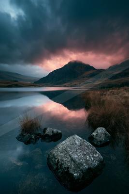 A moody water scene of lake, mountains.