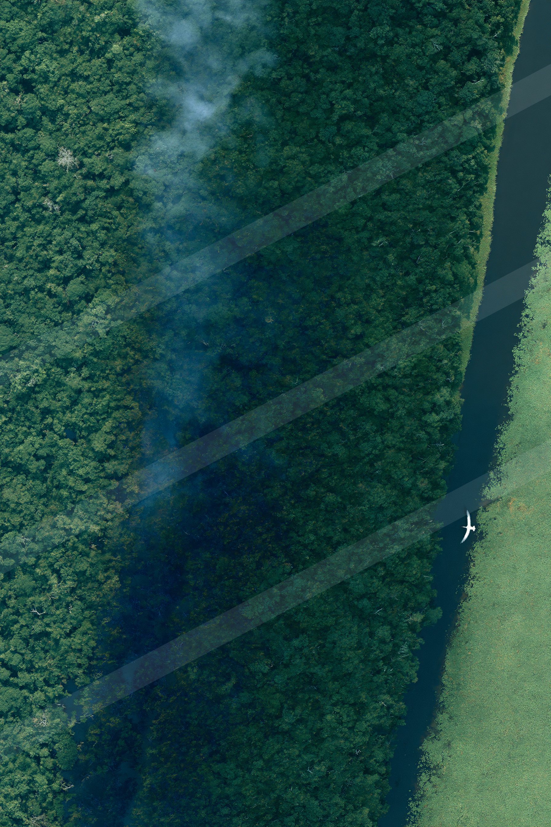 A moody aerial water scene of a river, smoke.