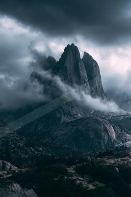 A gray-toned moody photograph of alp, valley, cliff.