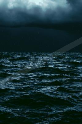 Dark turbulent ocean waves under a heavy overcast sky with visible rain falling during a storm