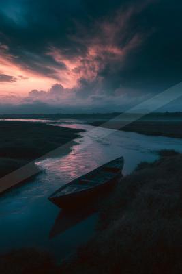 A black-toned moody photograph of canoe, sandbar, paddle.