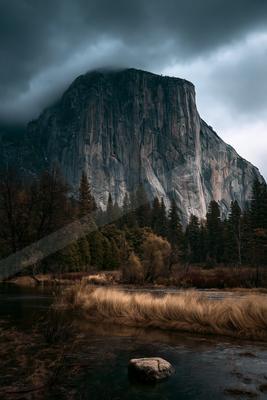 A brown-toned moody photograph of cliff, valley, alp.