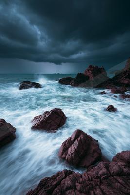 A dramatic long exposure water scene of an ocean, rocks.