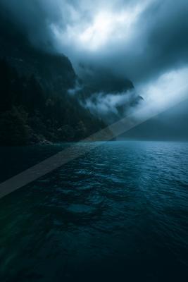 A black-toned moody photograph of cliff, promontory, seashore.