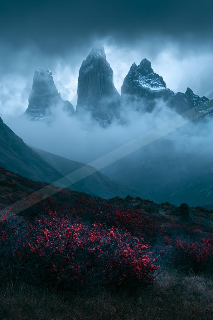 A dramatic landscape of mountains, fog.