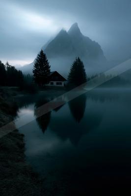 A serene long exposure water scene of lake, mountains, fog.