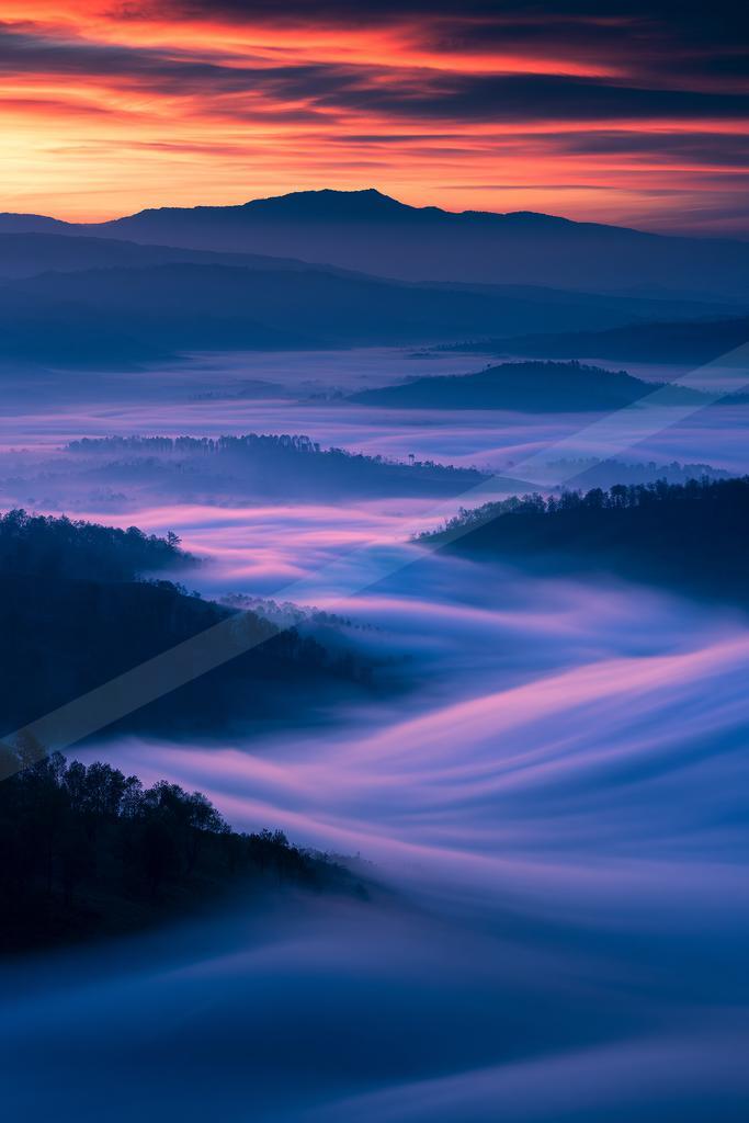A blue hour panorama landscape of a rolling hills, fog.