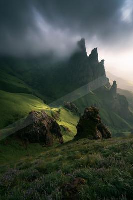 A moody landscape of mountains, valley, field.