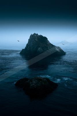 A blue hour water scene of ocean, fog.
