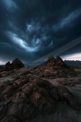 A black-toned moody photograph of volcano, seashore, cliff.