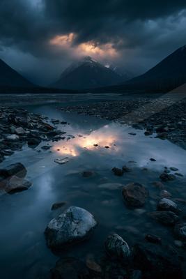 A blue hour long exposure water scene of lake, mountains, reflection.