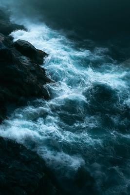 A black-toned moody photograph of promontory, seashore, cliff.