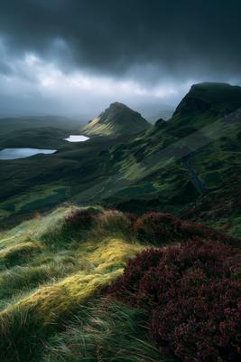 A moody landscape of mountains, valley, field.